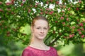 Closeup portrait of young natural beautiful redhead woman in fuchsia blouse posing against blossoming tree with blurred green foli Royalty Free Stock Photo