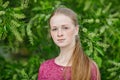 Closeup portrait of young natural beautiful redhead woman in fuchsia blouse posing against blossoming tree with blurred green foli Royalty Free Stock Photo