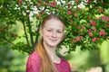 Closeup portrait of young natural beautiful redhead woman in fuchsia blouse posing against blossoming tree with blurred green foli Royalty Free Stock Photo