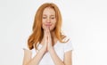 Closeup portrait of a young red head woman praying. Red hair beautiful girl isolated on white. Concentrated redhair woman in t- Royalty Free Stock Photo