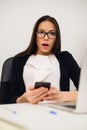 Closeup portrait young, shocked business woman, looking at cell phone seeing bad text message, email, isolated indoors Royalty Free Stock Photo