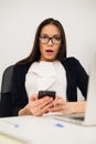 Closeup portrait young, shocked business woman, looking at cell phone seeing bad text message, email, isolated indoors Royalty Free Stock Photo