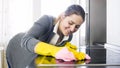 Closeup portrait of young smiling housewife cleaning cooking hob on kitchen