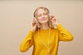 Closeup portrait of young woman closed eyes listening music via headphones on beige wall. Royalty Free Stock Photo