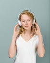 Closeup portrait of young woman closed eyes listening music via headphones on color neutral gray tone Royalty Free Stock Photo