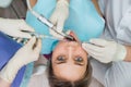 Closeup portrait of young woman getting dental treatment, hands of dentist and assistant makes treatment procedures to Royalty Free Stock Photo