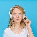 Closeup portrait of young woman listening music via headphones on color bright blue tone Royalty Free Stock Photo