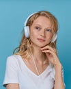 Closeup portrait of young woman listening music via headphones on color bright blue tone wall Royalty Free Stock Photo