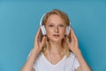 Closeup portrait of young woman listening music via headphones on color bright blue tone wall Royalty Free Stock Photo