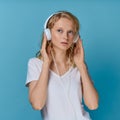 Closeup portrait of young woman listening music via headphones on color bright blue tone wall Royalty Free Stock Photo