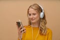 Closeup portrait of young woman listening music via headphones on yellow beige tone wall Royalty Free Stock Photo