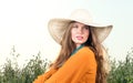 Closeup portrait of young woman sitting in a field. Straw hat and red dress Royalty Free Stock Photo