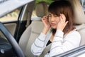 Closeup portrait of young woman touching her temple feels headache in her car after driving car for long time. Royalty Free Stock Photo