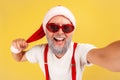 Closeup positive smiling gray bearded man in sunglasses and santa claus hat looking at camera with toothy smile, posing making