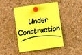 Closeup post it note on corkboard with under construction message on it