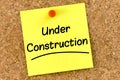 Closeup post it note on corkboard with under construction message on it Royalty Free Stock Photo