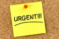 Closeup post it note on corkboard with urgent message on it Royalty Free Stock Photo