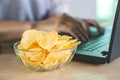 Potato chips in bowl on office desk with blur background of woman working with computer