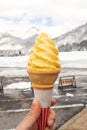 Woman holding yellow softcream with snow background. Royalty Free Stock Photo