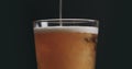 Closeup pour light ale beer in pint glass over black background Royalty Free Stock Photo