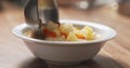 Closeup pouring cauliflower soup into bowl on wood table