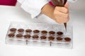 Closeup pouring melted chocolate into mold with pastry bag, hand-crafted candy