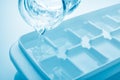 Closeup pouring fresh drink water from a jug into ice cube tray Royalty Free Stock Photo