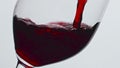 Closeup pouring red wine glass indoors. Alcoholic liquid filling wineglass