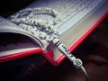 Closeup of praying beads with arabic calligraphy on an opened holy book of Quran or Koran Royalty Free Stock Photo