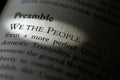 Closeup of the Preamble, We the People of the United States, printed and highlighted in textbook on white page.