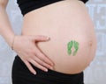 Closeup of pregnant belly with baby feet stamp