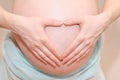 Pregnant woman making heart-shape sign with her hands on her big belly. Concept of love, expecting child and parenting Royalty Free Stock Photo