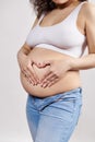 Closeup pregnant woman putting hands on naked belly, making heart shape from fingers. Happy carefree pregnancy 30 week Royalty Free Stock Photo