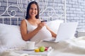 Pregnant woman sitting on bed with laptop and credit card Royalty Free Stock Photo