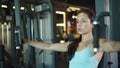 Pretty fit girl using simulator in sport club. Woman making bicep curls at gym Royalty Free Stock Photo