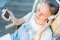 Closeup of pretty teen girl in headphones listening to music using a laptop outside on the terrace in the garden Royalty Free Stock Photo