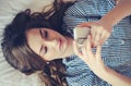 Closeup of pretty teenage girl lying in bed an looking at her mobile phone Royalty Free Stock Photo