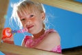 A Closeup of a pretty, young girl wearing a pink dress, about to blow bubbles from the top of her climbing frame, on a sunny Royalty Free Stock Photo
