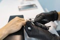 Closeup process of professional manicure. Manicurist woman hands in black gloves making manicure using professional tools. Nail