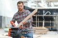 Closeup professional carpenter hold electric circular saw at sawmill. Skilled joiner using circular saw for cutting wood Royalty Free Stock Photo
