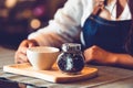 Closeup of professional female barista hand making and holding white cup of coffee. Happy young woman at counter bar in restaurant Royalty Free Stock Photo