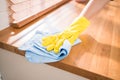 Closeup professional hands of Asian woman cleaning service wearing yellow rubber gloves, using a rag to wipe on the wooden. Royalty Free Stock Photo