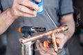 Closeup professional master plumber holding flux paste for soldering and brazing seams of copper pipe gas burner. Concept Royalty Free Stock Photo