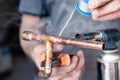 Closeup professional master plumber holding flux paste for soldering and brazing seams of copper pipe gas burner. Concept Royalty Free Stock Photo
