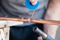 Closeup professional master plumber holding flux paste for soldering and brazing seams of copper pipe gas burner. Concept Royalty Free Stock Photo