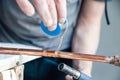 Closeup professional master plumber holding flux paste for soldering and brazing seams of copper pipe gas burner. Concept Royalty Free Stock Photo