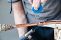 Closeup professional master plumber holding flux paste for soldering and brazing seams of copper pipe gas burner. Concept Royalty Free Stock Photo