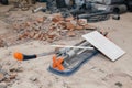 Closeup professional metal construction tile cutter and lying on the floor on dusty construction site. Concept decoration and