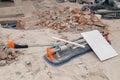 Closeup professional metal construction tile cutter and lying on the floor on dusty construction site. Concept decoration and