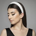 Closeup profile of confident young woman with hairband looking forward isolated on gray background